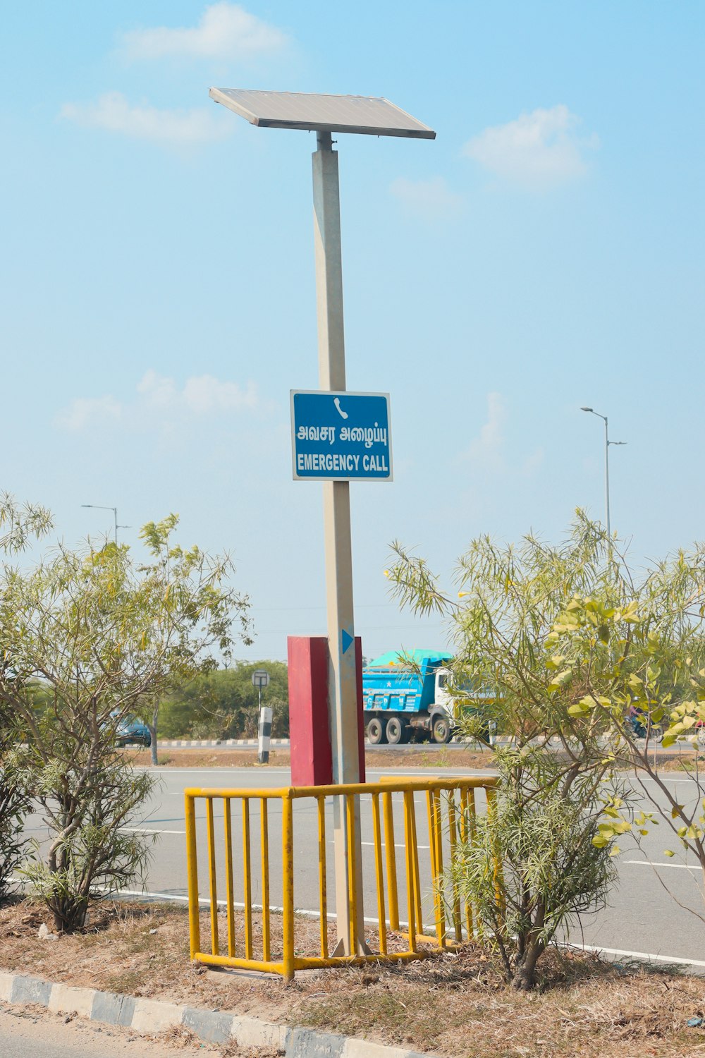 a blue and white sign on a pole next to a road