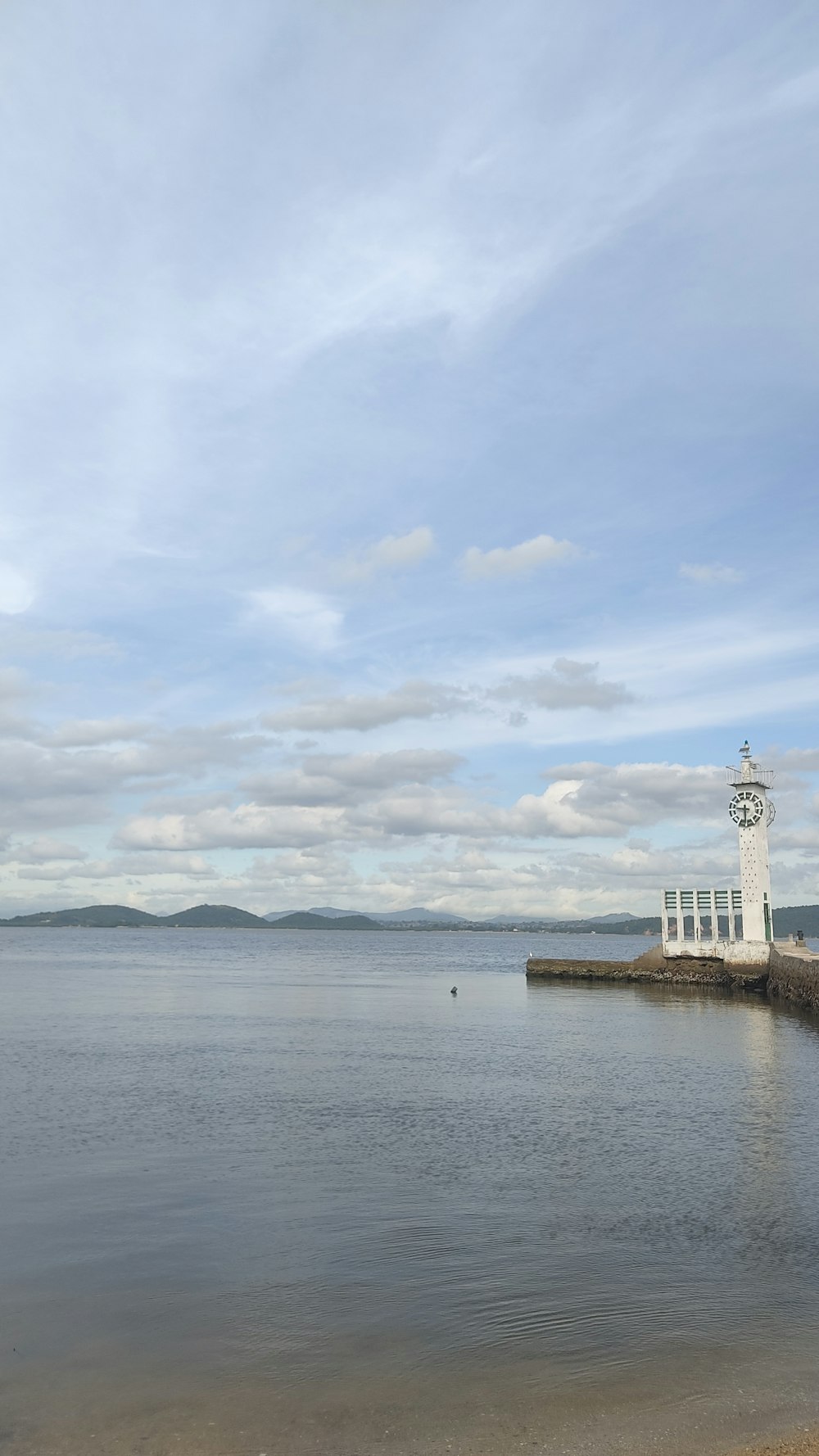 a light house sitting on the edge of a body of water