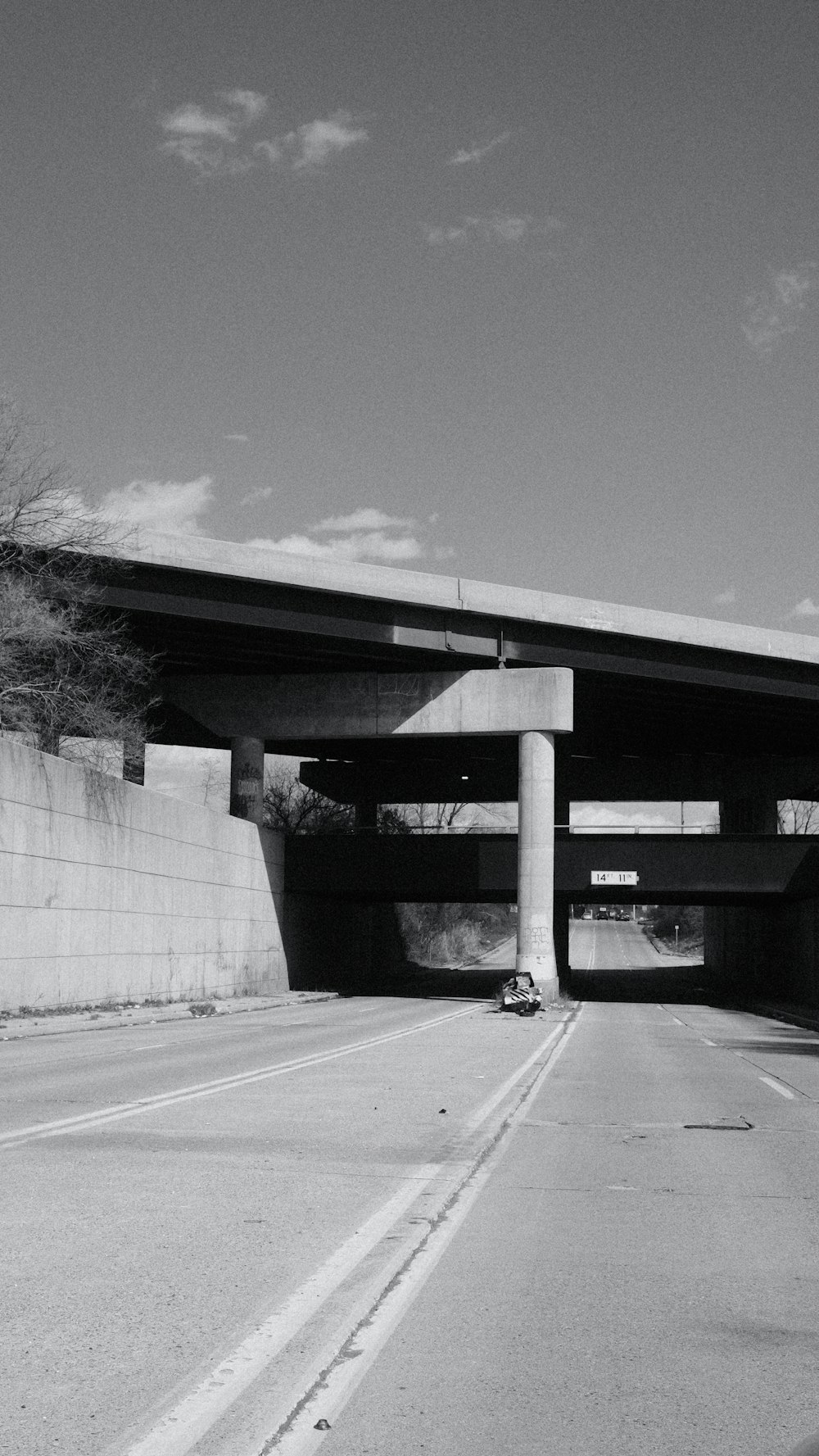 a black and white photo of a highway under a bridge