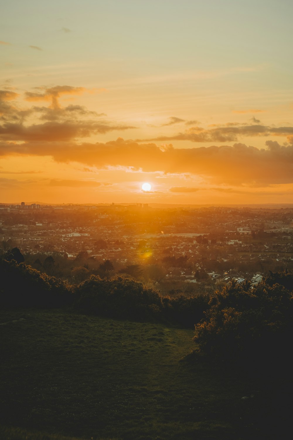 the sun is setting over a city and hills