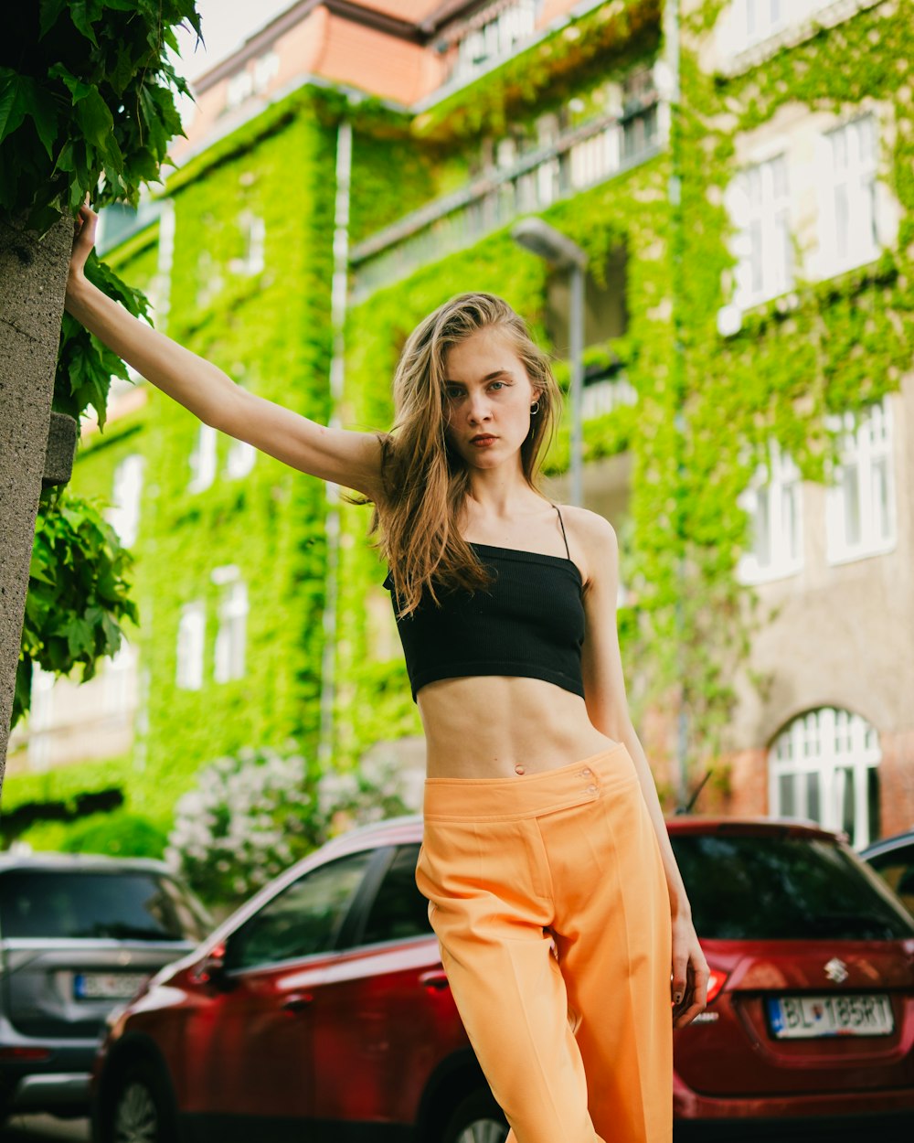 a woman standing next to a tree in front of a building