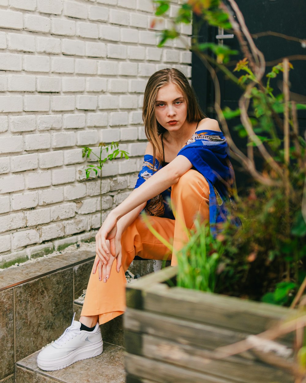 a woman sitting on a step in front of a brick wall