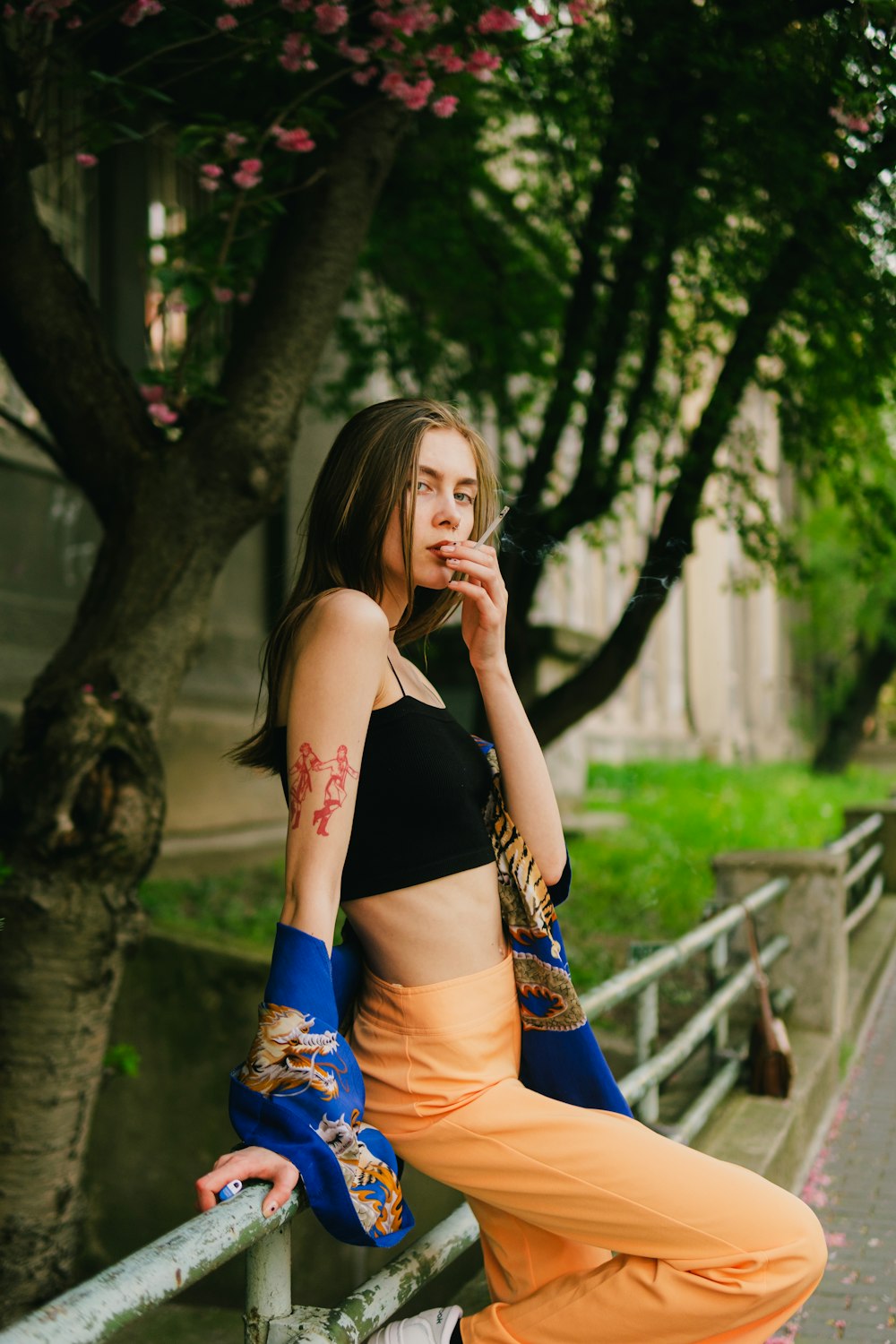 a woman sitting on a rail smoking a cigarette