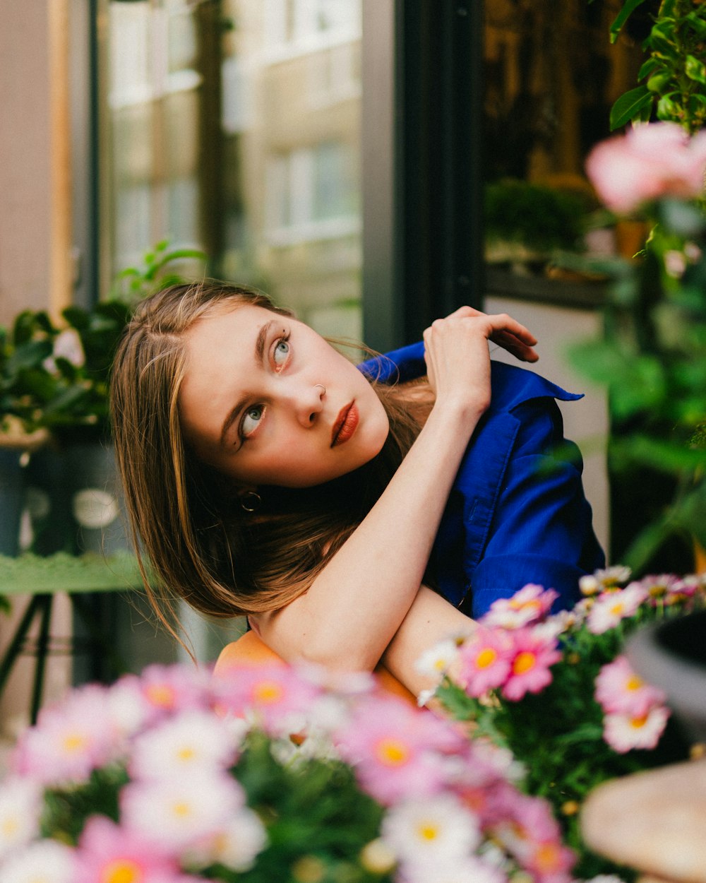 a woman sitting on a bench next to a bunch of flowers