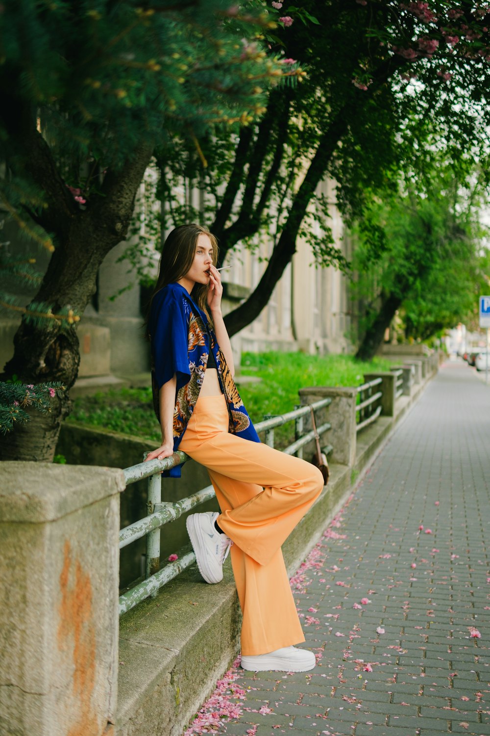 a woman leaning on a fence talking on a cell phone