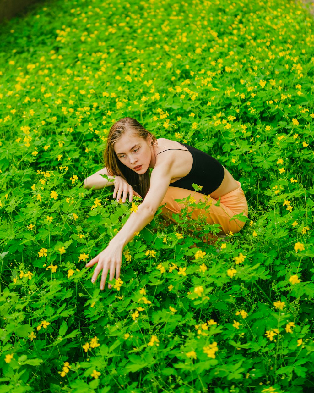 a woman kneeling in a field of yellow flowers