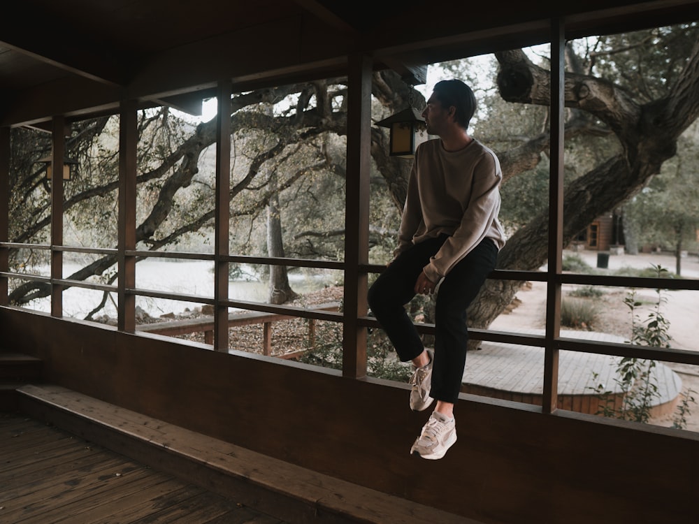 a man standing on a window sill in front of a tree