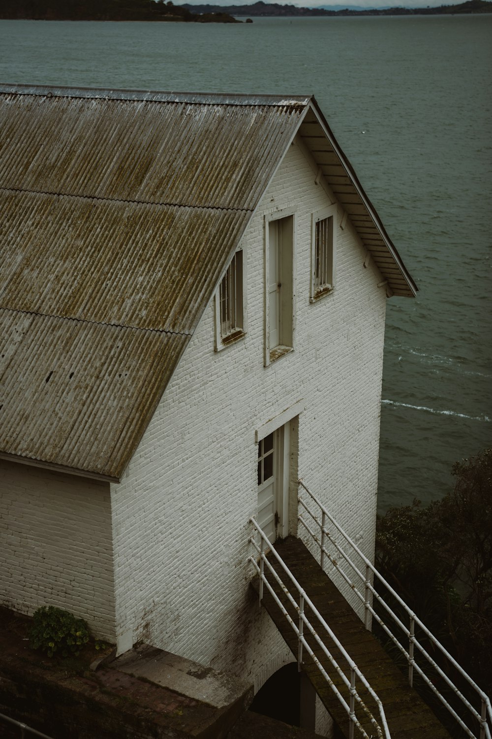 a white building with a brown roof next to a body of water