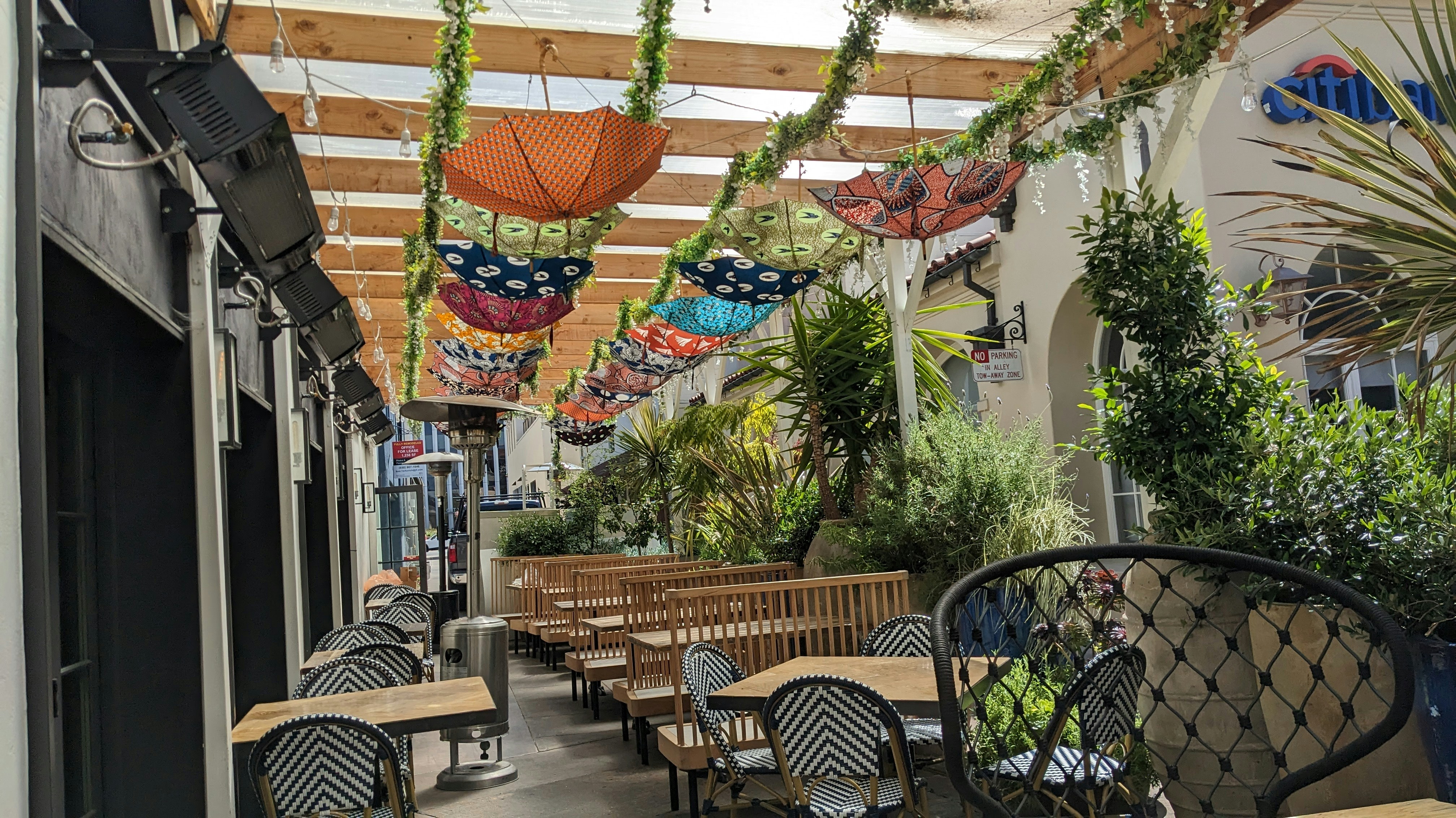 Vibrant outdoor Phoenix patio dining scene with bright warm lighting, lush greenery, and happy diners enjoying Arizona weather