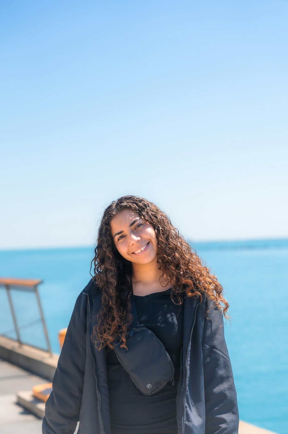 a woman standing on a pier next to the ocean