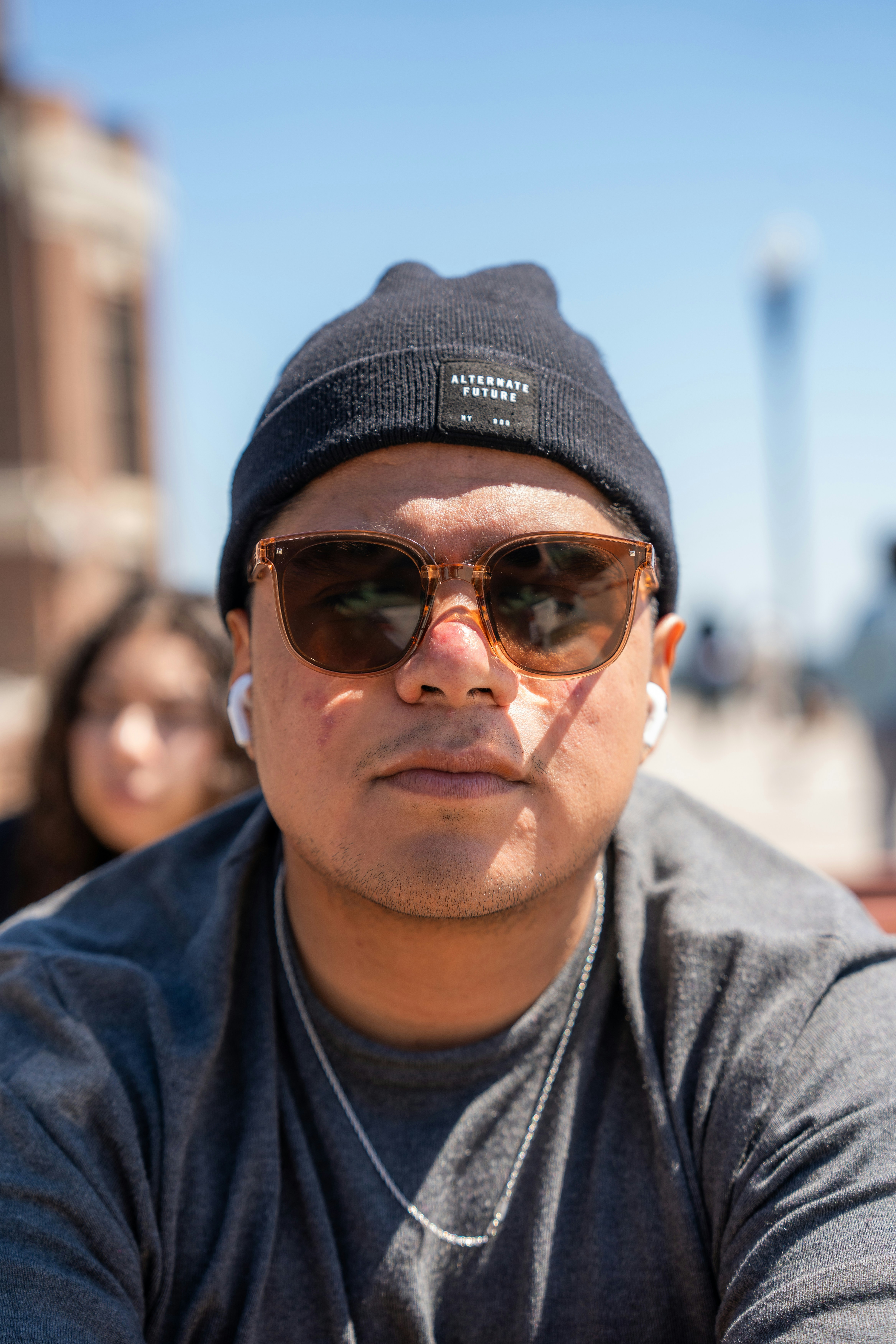 a man wearing sunglasses and a beanie looks at the camera