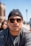 a man wearing sunglasses and a beanie looks at the camera