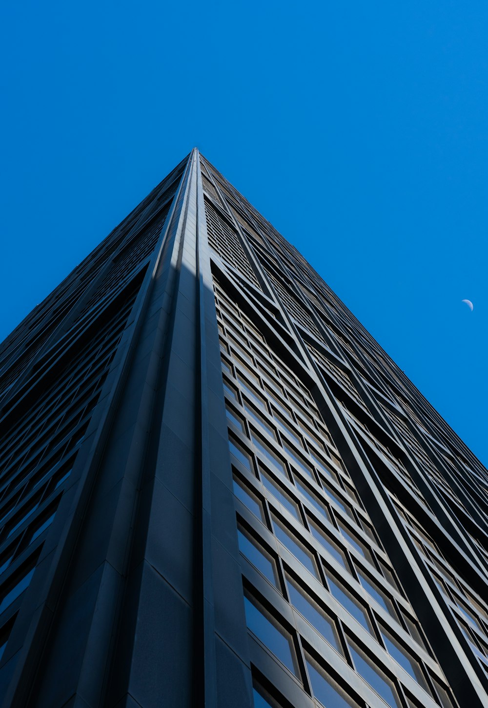 a tall building with a half moon in the sky