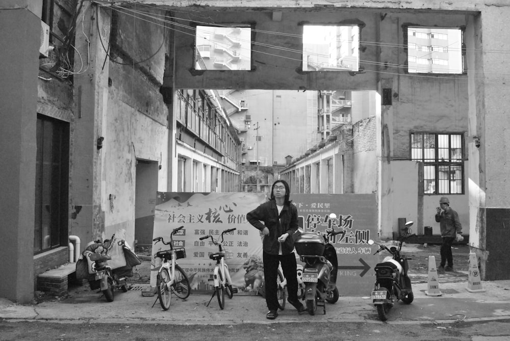 a black and white photo of a man standing in an alley