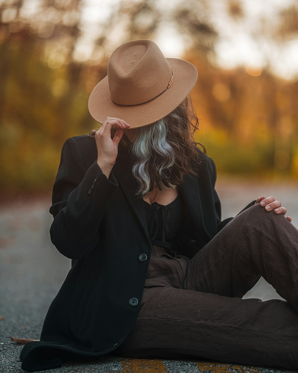 a woman sitting on the ground wearing a hat