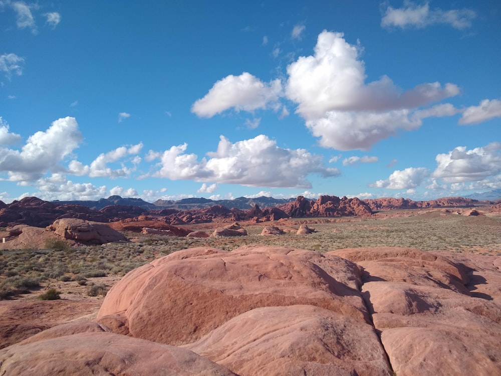 a view of a desert with rocks and mountains in the background