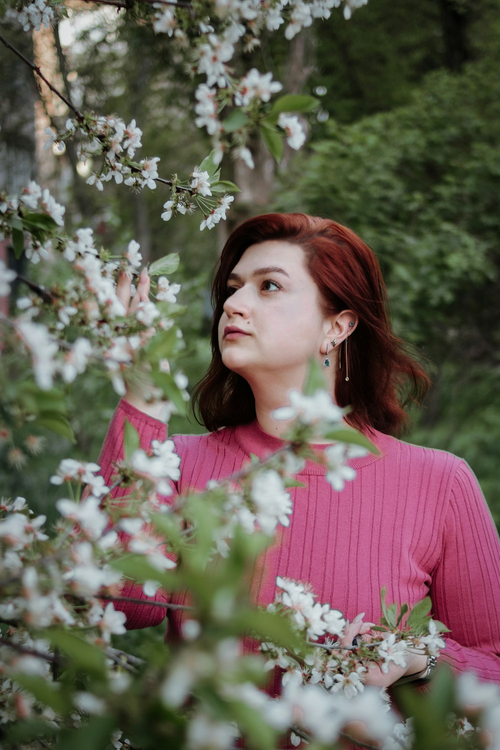 a woman in a pink sweater standing in a tree