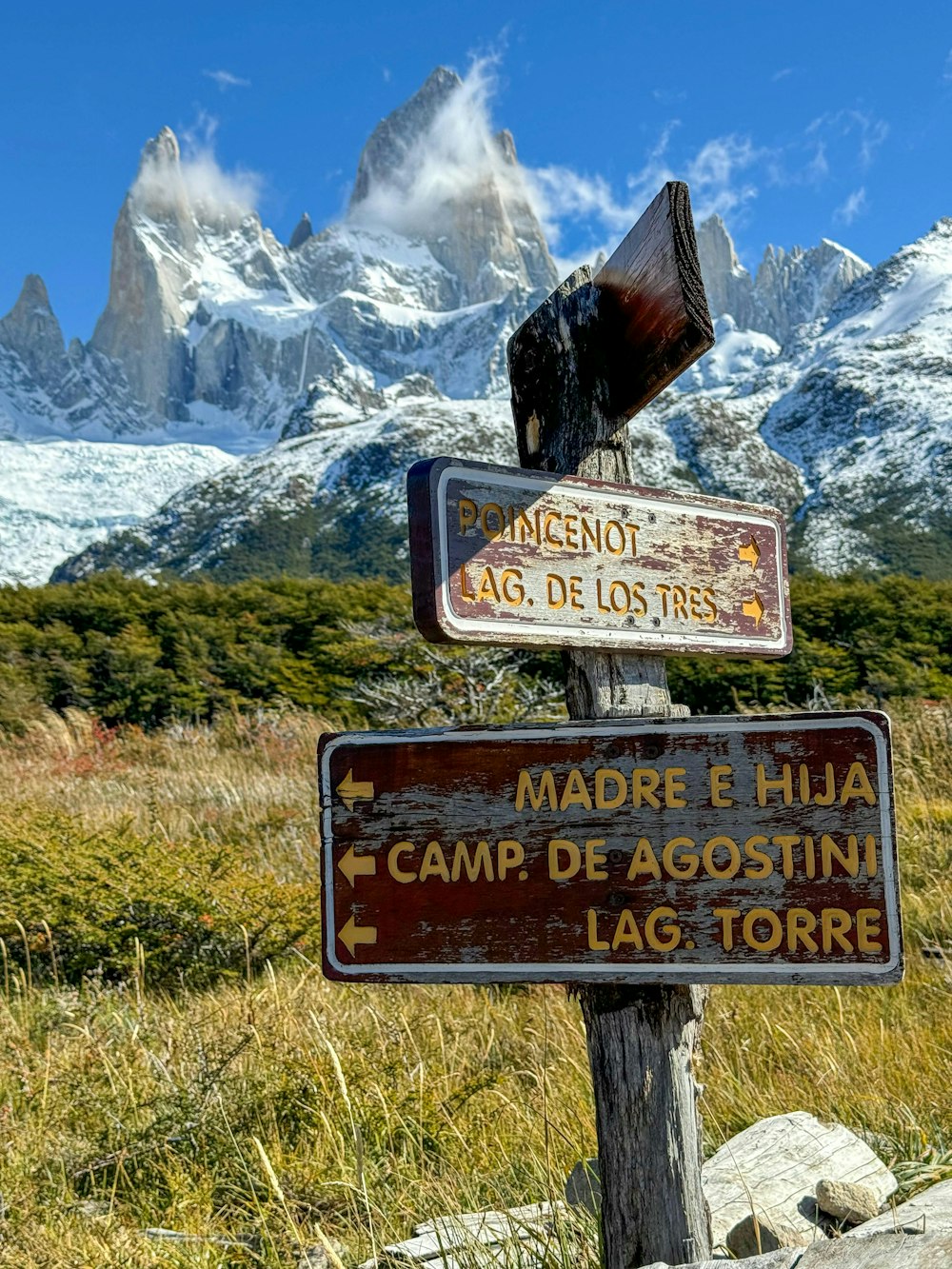 un cartello di legno con una montagna sullo sfondo