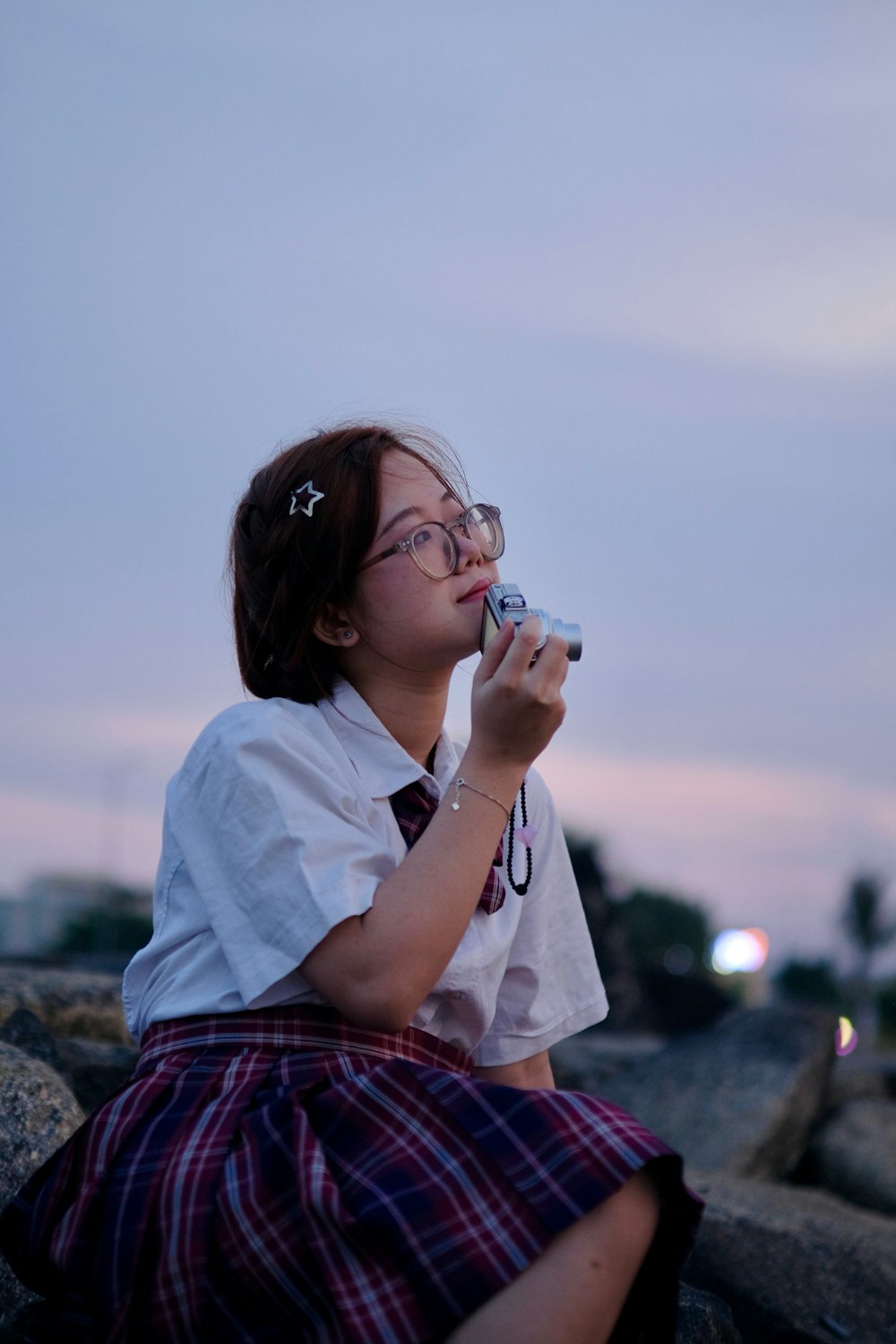 a woman sitting on a rock with a cell phone in her hand