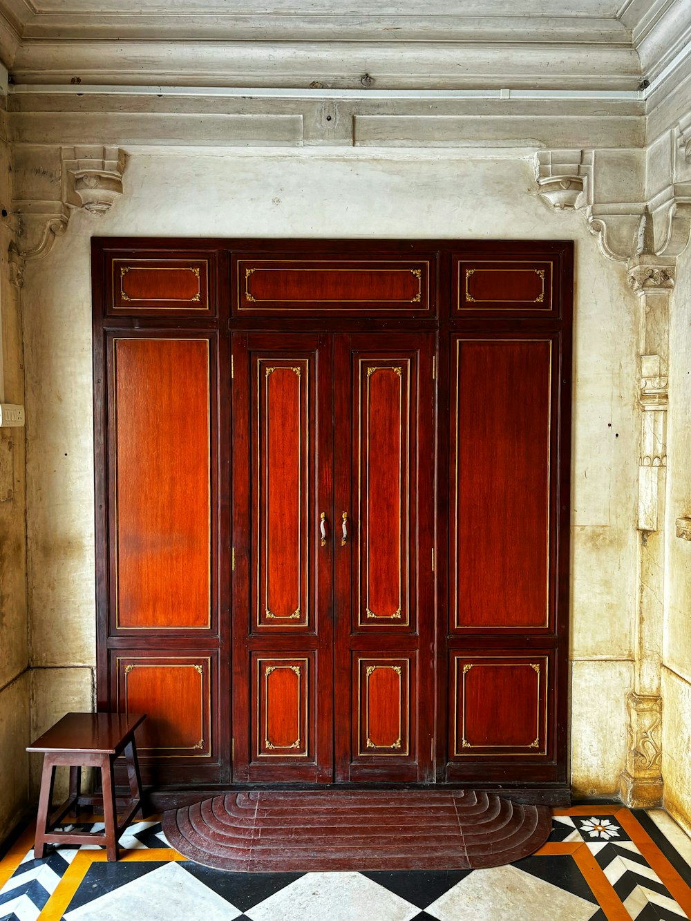 a room with a large wooden door and a chair