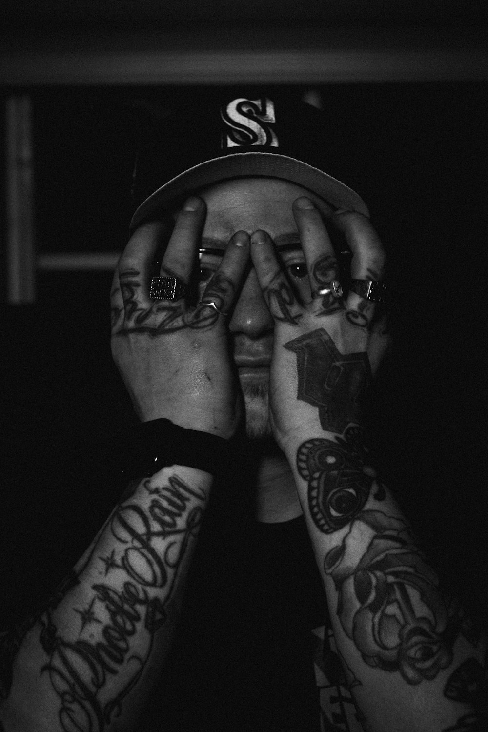 a man with tattoos covering his face with his hands