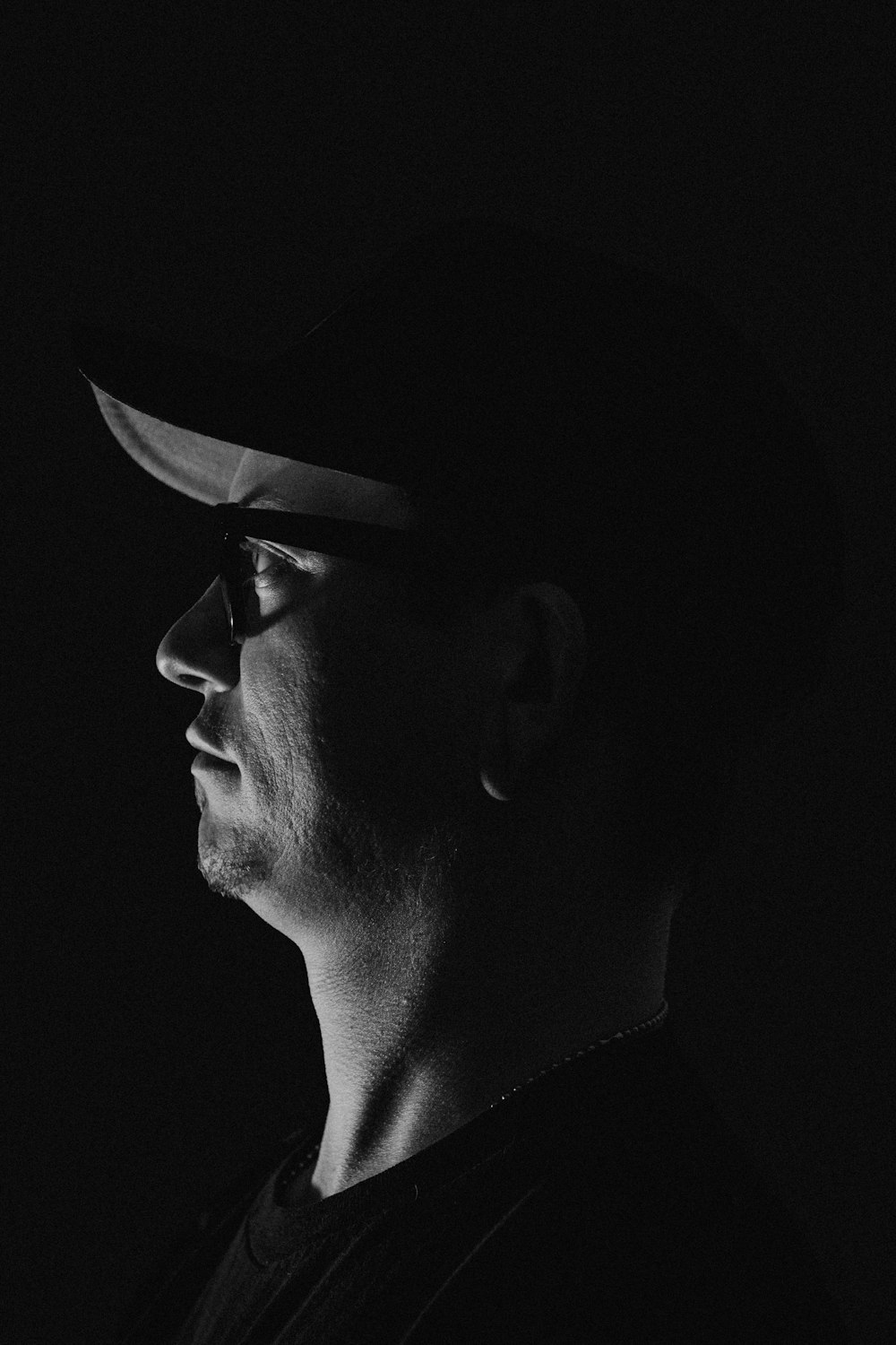 a man wearing a hat and glasses in the dark