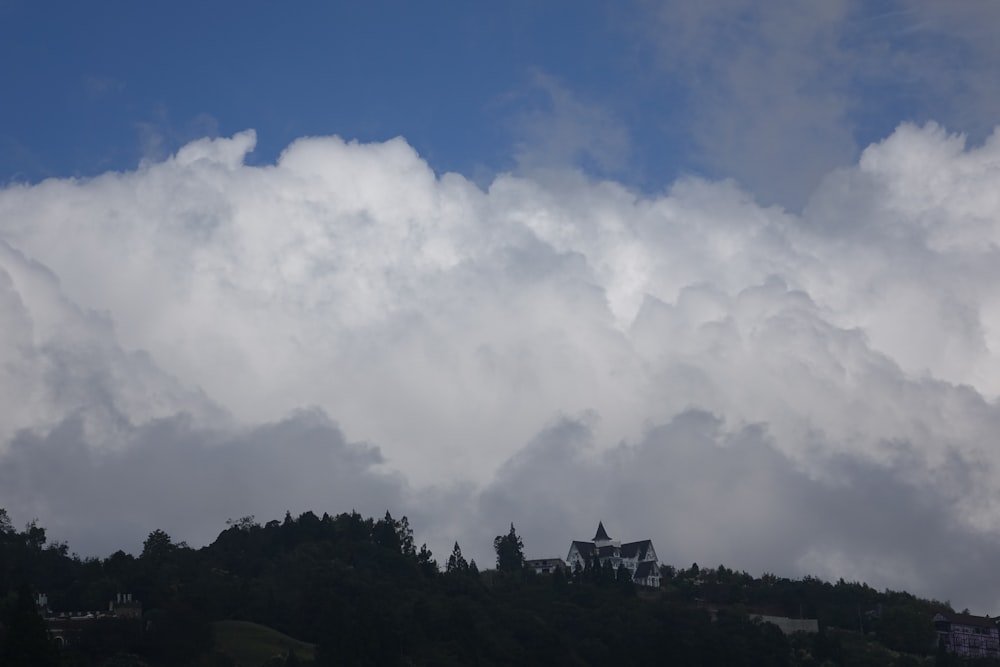 a cloud filled sky with a house on a hill in the foreground