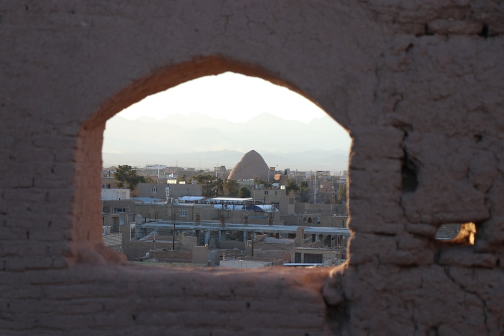 a view of a city through a hole in a wall