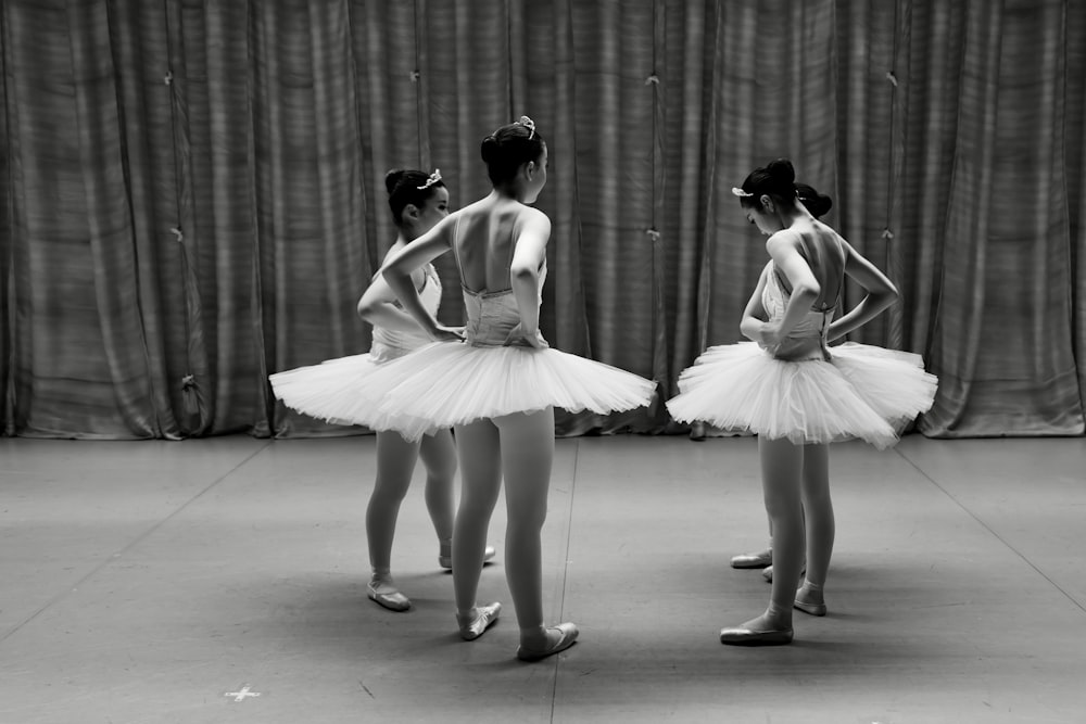 a group of young ballerinas standing in front of a curtain