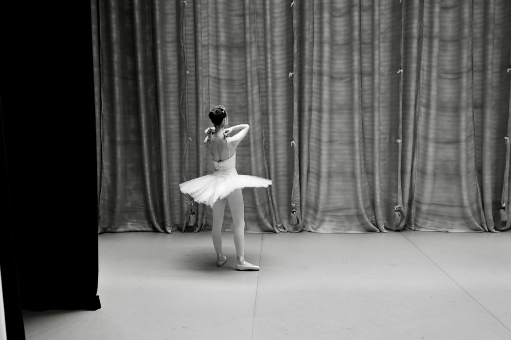 a woman in a white tutu standing in front of a curtain