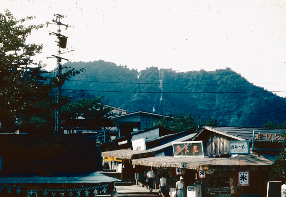 a group of people walking down a street next to a forest