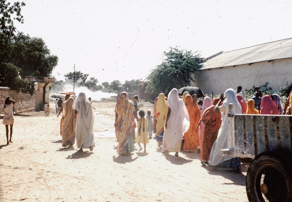 a group of women walking down a dirt road