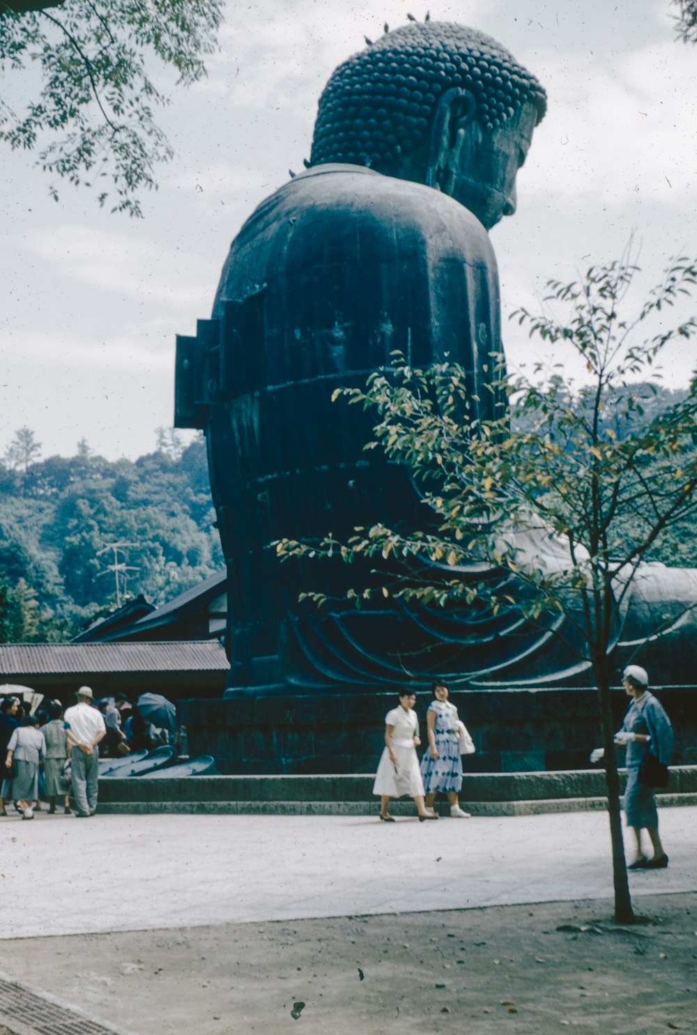 a group of people standing around a giant buddha statue