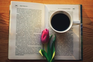 a cup of coffee and a flower on a book