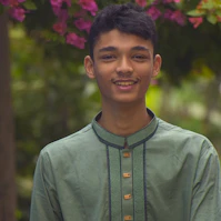 a young man standing in front of a tree