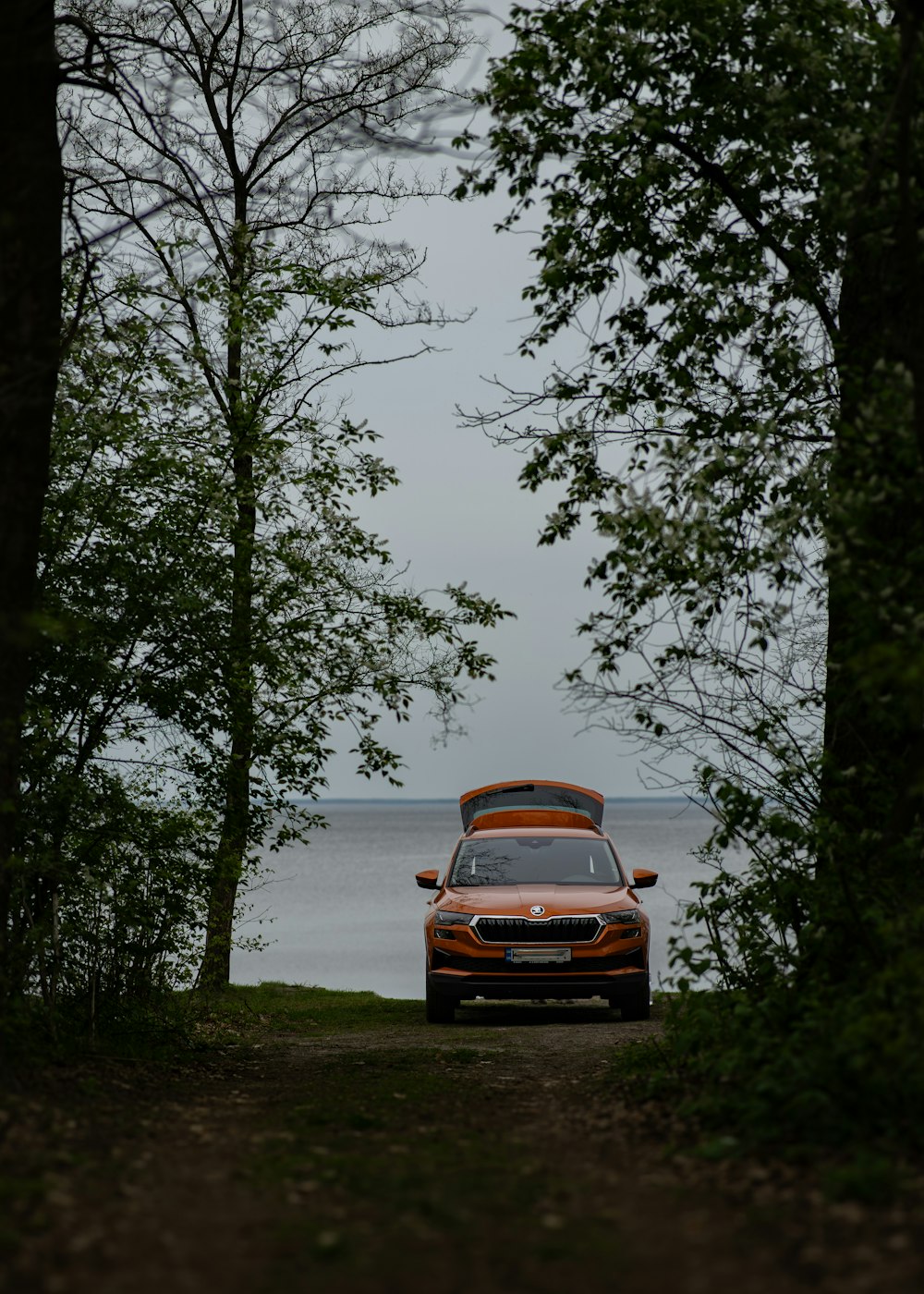 a car parked on a dirt road next to a body of water