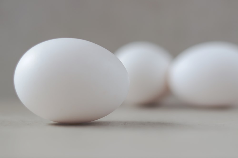 eine Gruppe weißer Eier, die auf einem Tisch sitzen