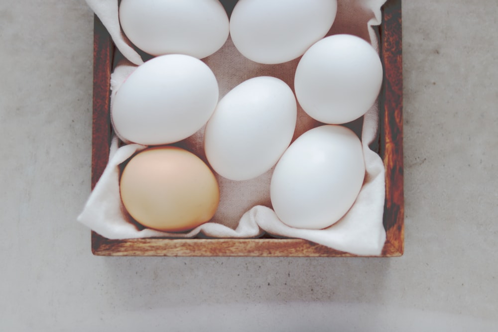 a wooden box filled with white eggs on top of a table