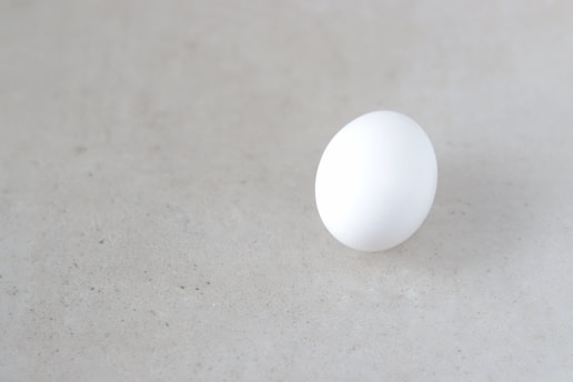 a white egg sitting on top of a white table