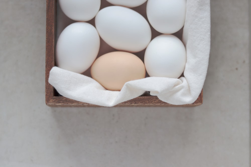 a wooden box filled with white eggs on top of a table