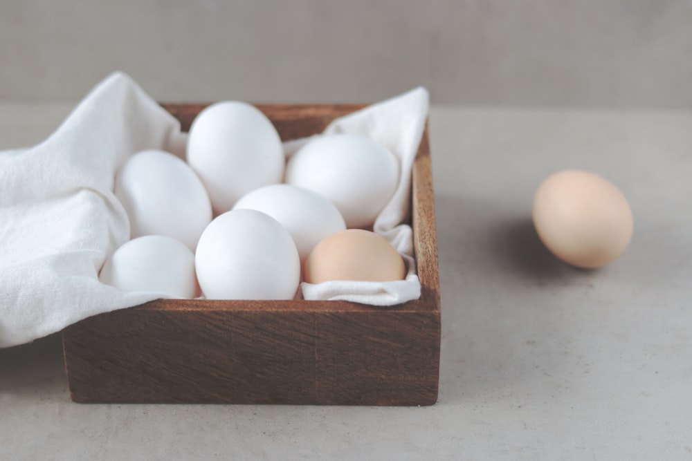 una caja de madera llena de huevos blancos y marrones