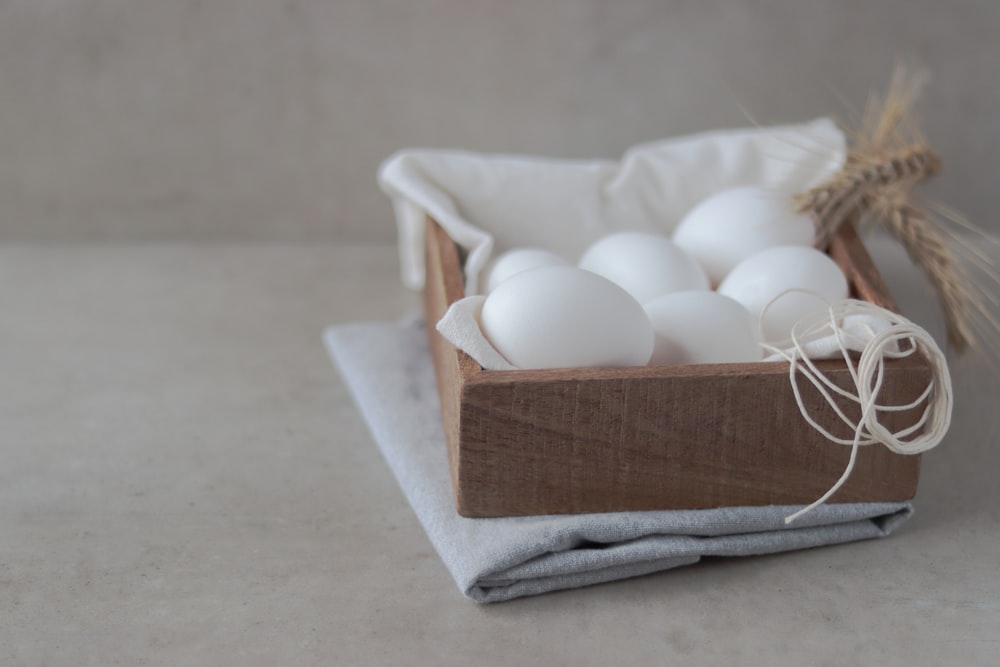 a wooden box filled with white eggs on top of a table