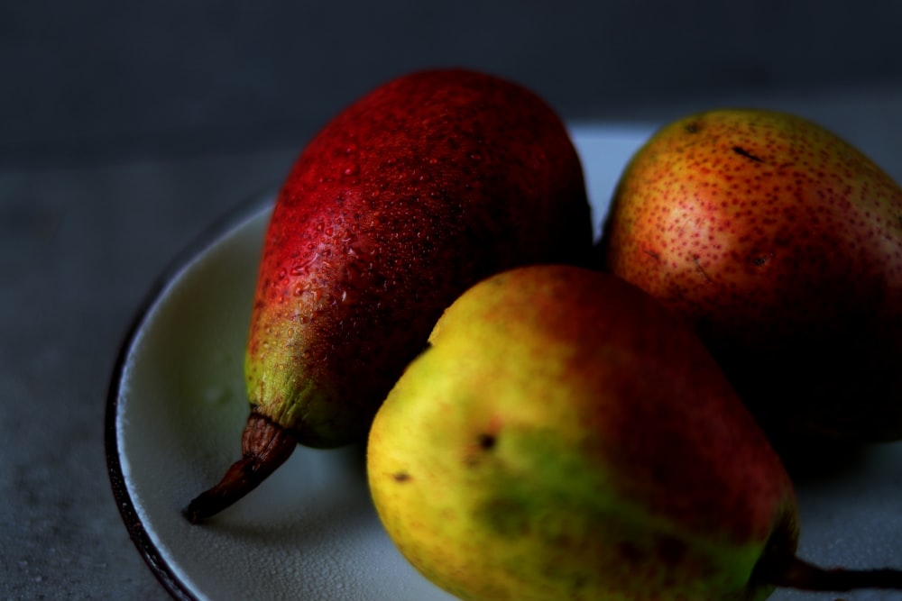 three pears on a plate on a table