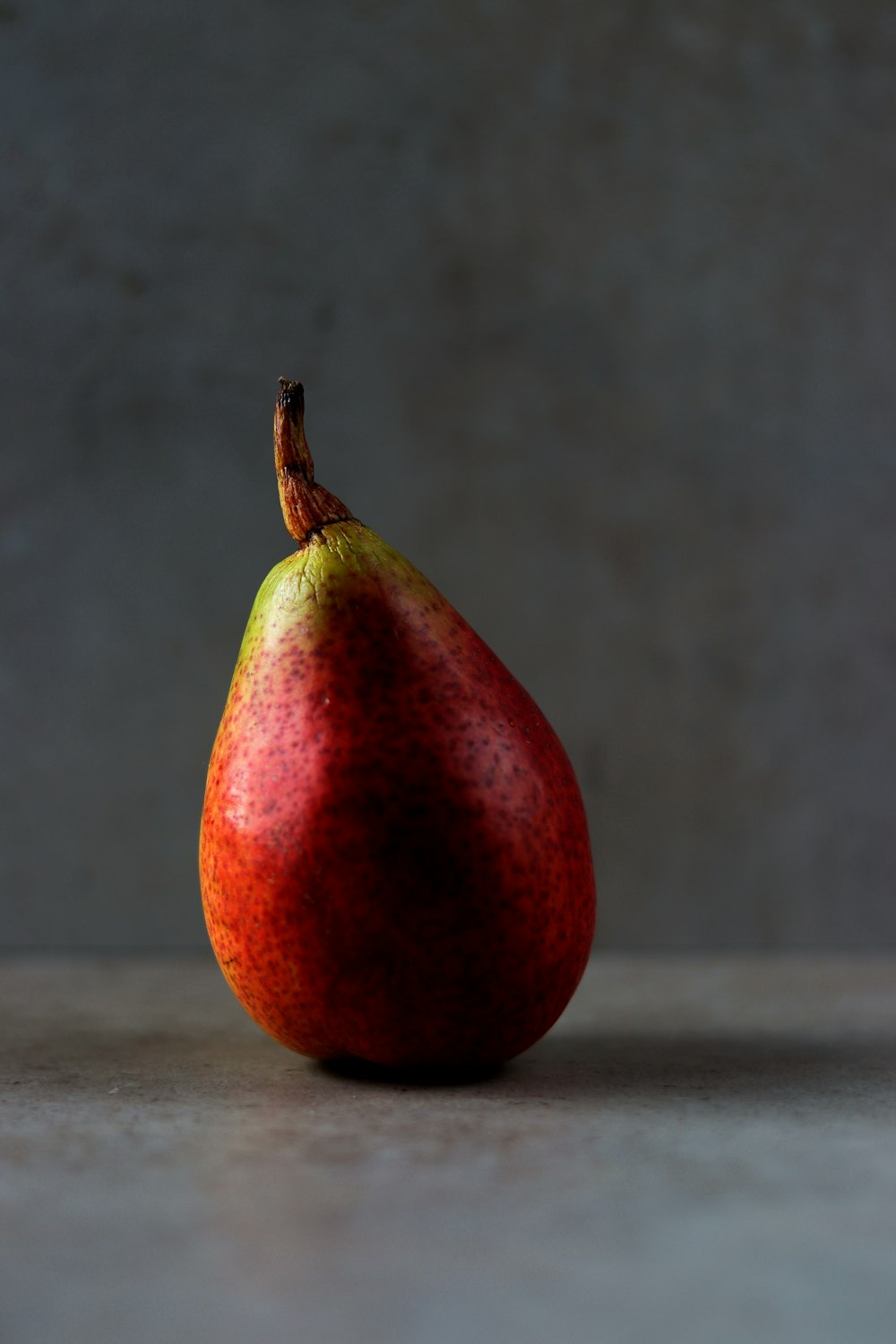 a red and green pear sitting on top of a table