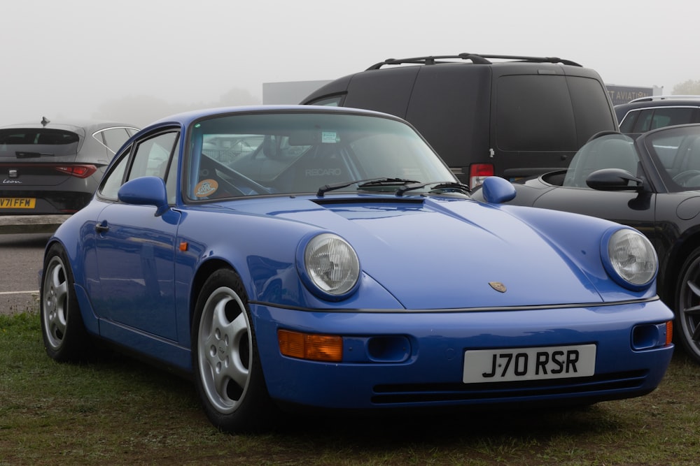 a blue porsche parked next to other cars