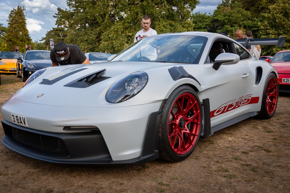 a man standing next to a white sports car