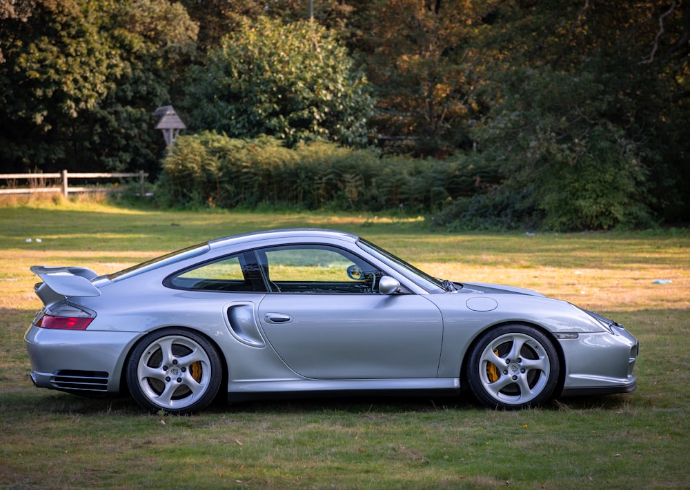 a silver sports car parked in a grassy field