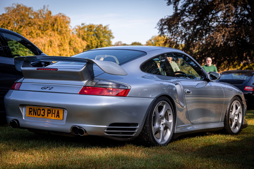 a silver sports car parked in the grass