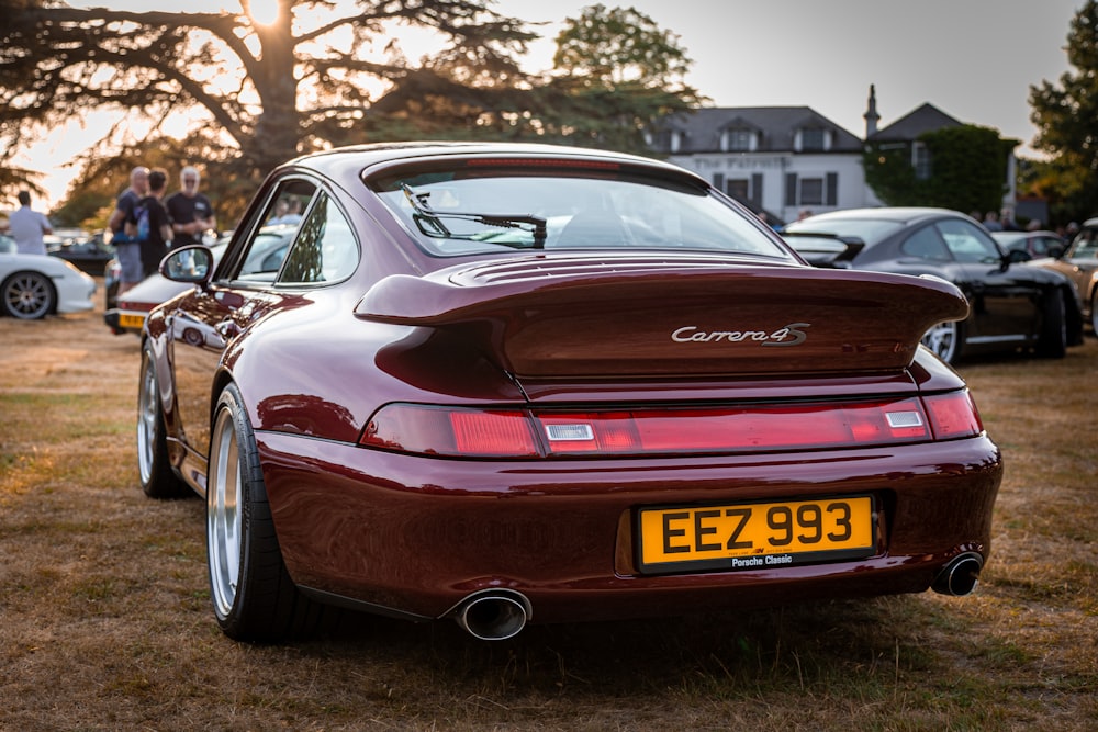 a maroon sports car parked in a field