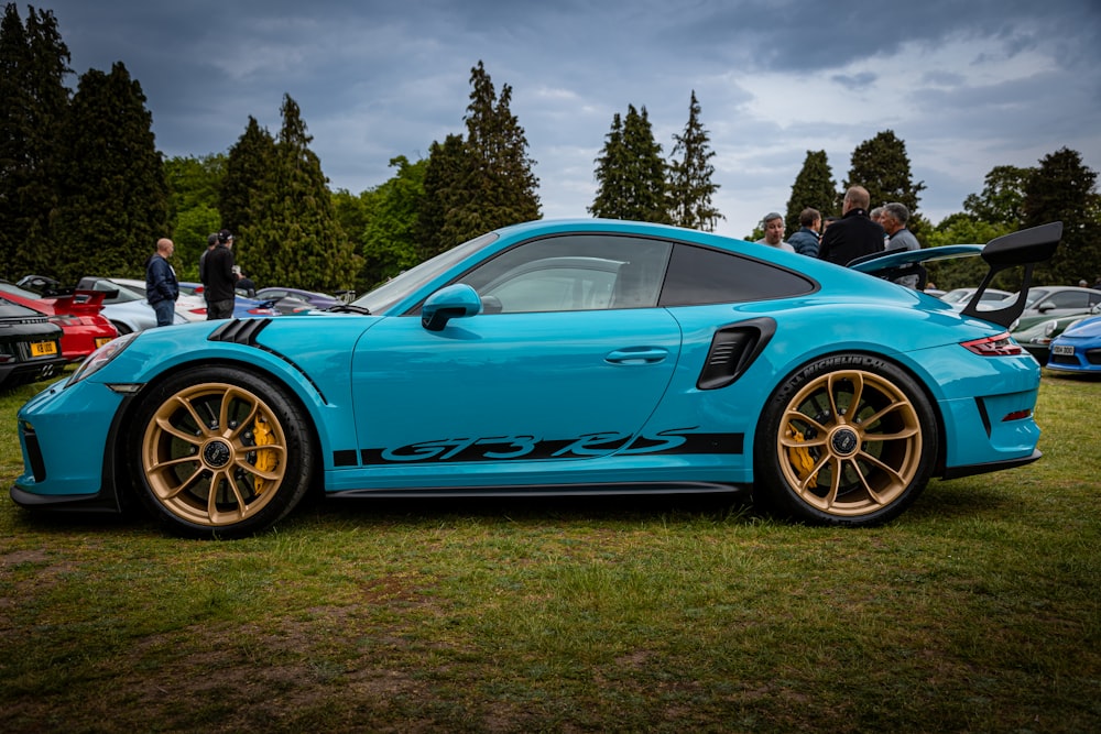 a blue sports car parked on top of a lush green field